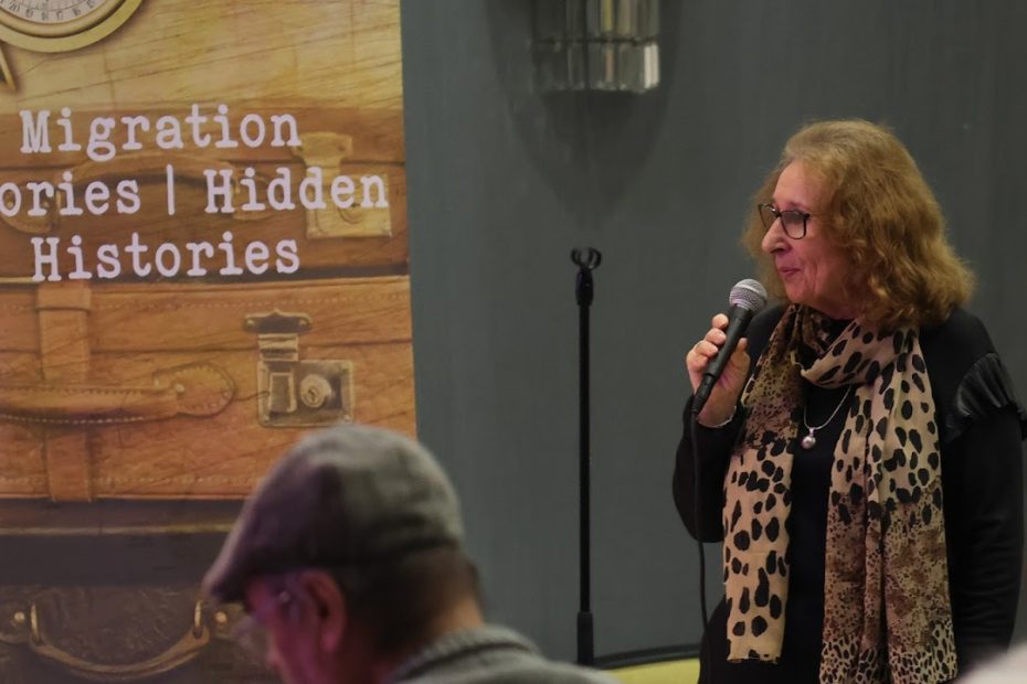 Claudette standing with a microphone with a hidden histories banner behind her